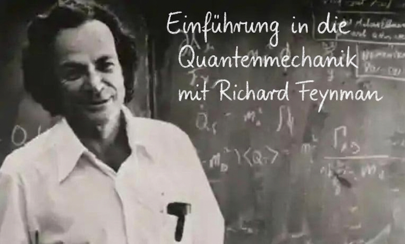 Richard Feynman steht vor einer Tafel mit Formeln.