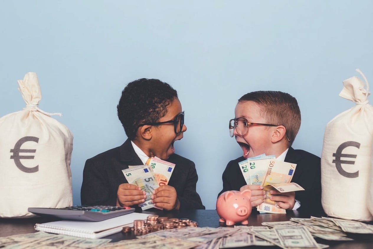 Dos niños sosteniendo dinero y gritando de emoción el uno al otro