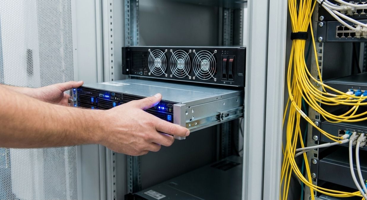 Installation d'un nouveau serveur dans une armoire avec de l'équipement informatique.