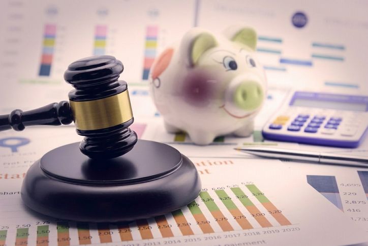 Un maillet à côté d’une tirelire et d’une calculatrice pour représenter les règlements financiers