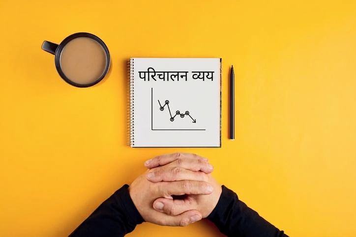नोटबुक पर घटते ऑपरेटिंग खर्च, साथ में कॉफी मग और किसी पुरुष के हाथ