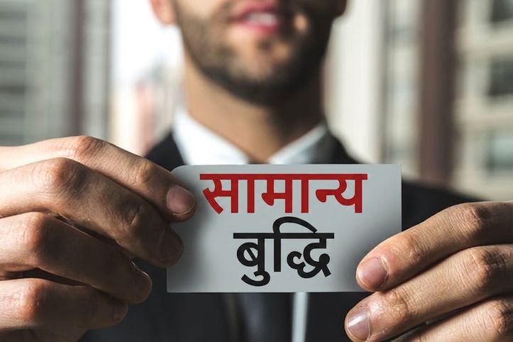 एक व्यक्ति "common sense" लिखे लेबल को उठाए हुए