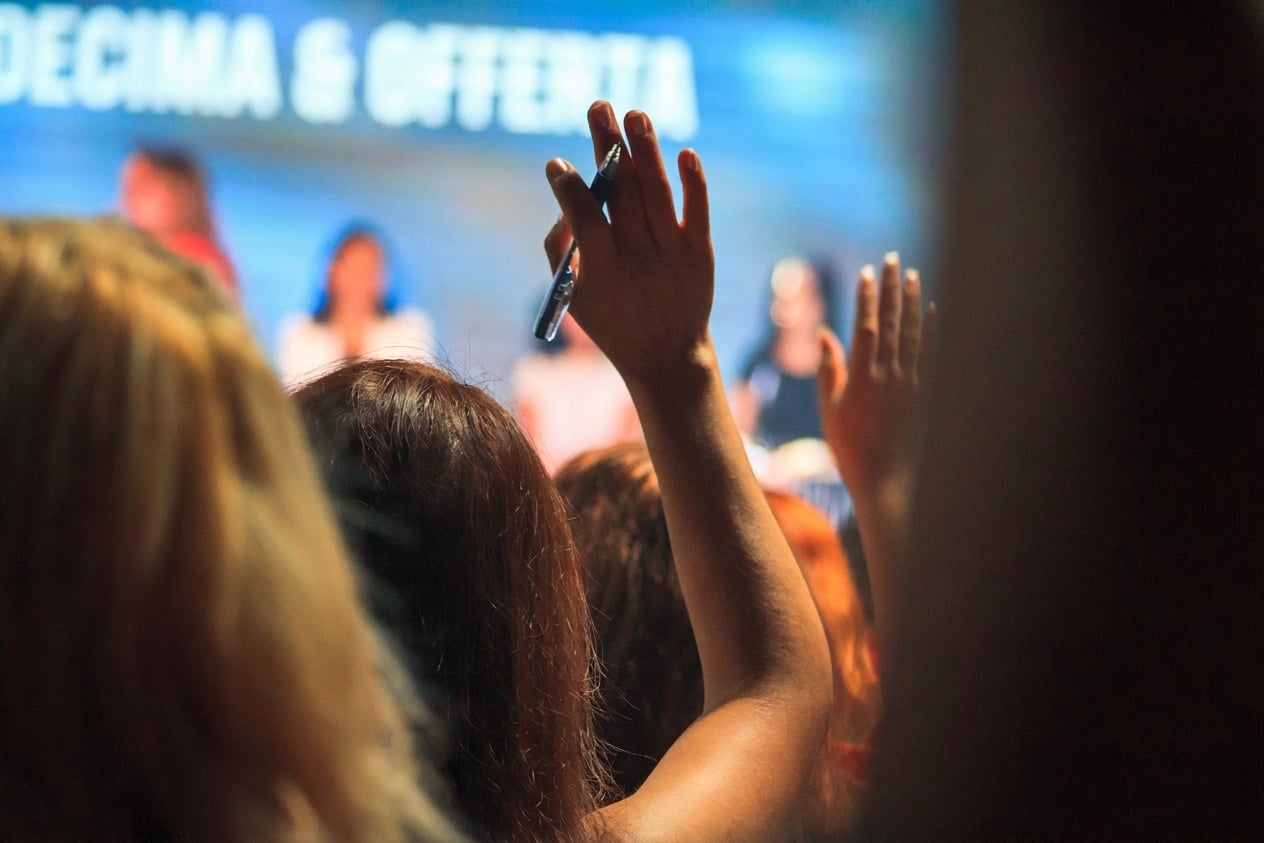 persona tra il pubblico che alza la mano per fare una domanda a un panel