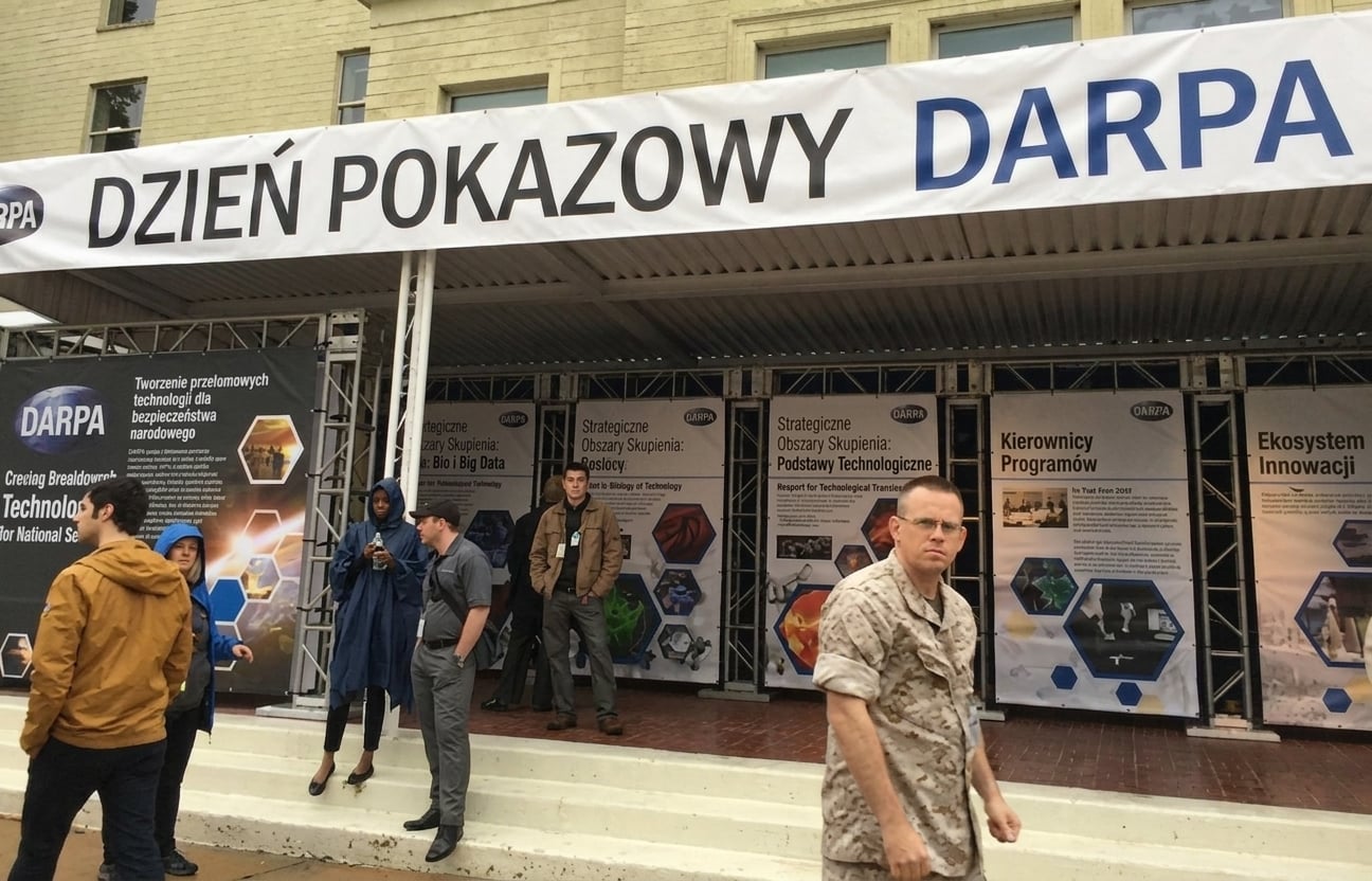 Stoiska wystawiennicze na konferencji z banerem z napisem „DARPA Demo Day"
