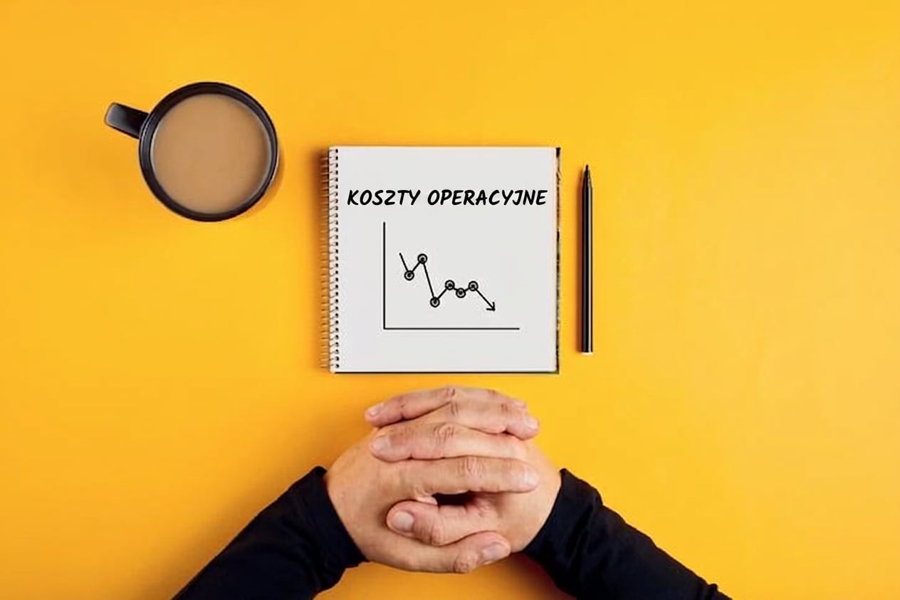 Notatnik z wykresem malejących kosztów operacyjnych, kubek kawy i ręce mężczyzny