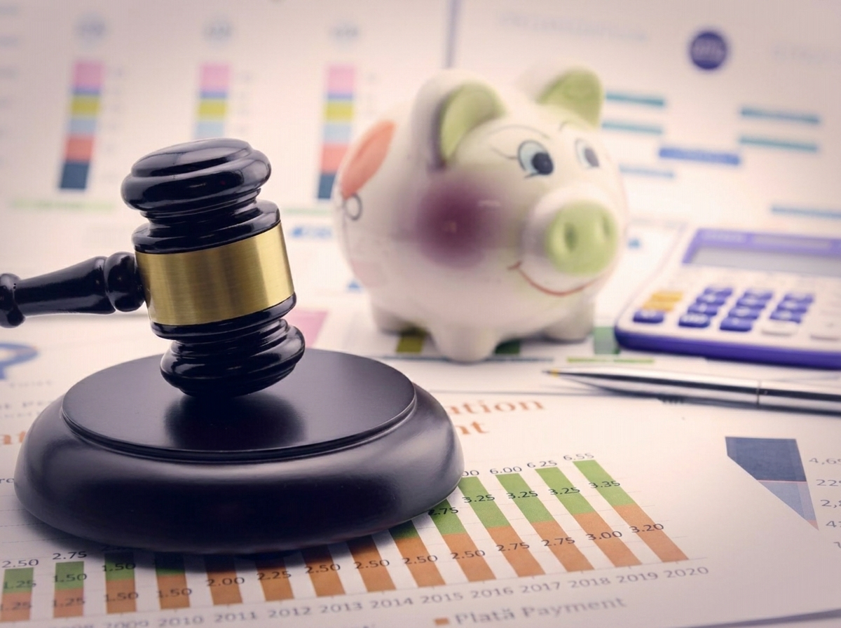 Un ciocan de judecător lângă o pușculiță și un calculator, reprezentând reglementările financiare