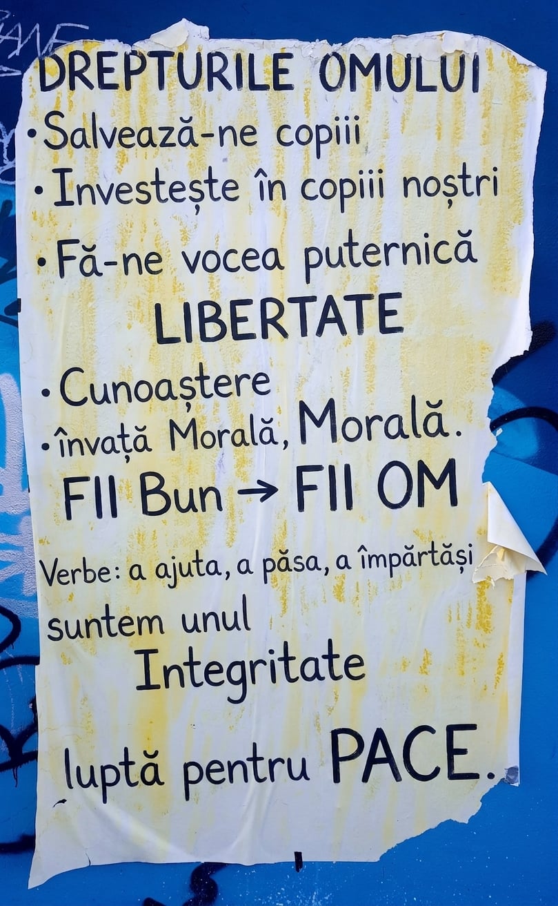 Fotografie a unui afiș rupt pe un perete cu declarații etice.