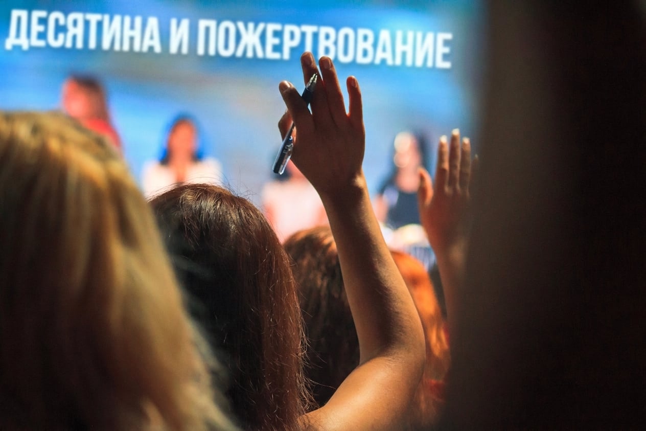 Человек в зале поднимает руку, чтобы задать вопрос участникам панели