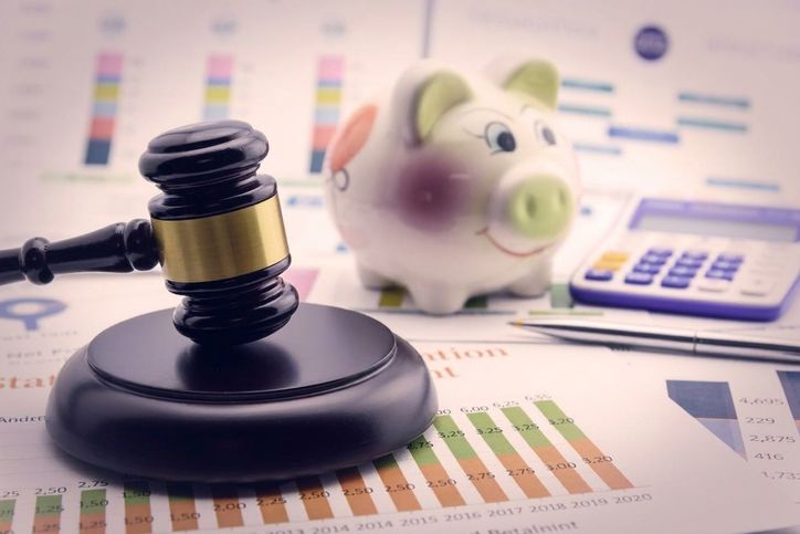 En klubba bredvid en spargris och miniräknare som symboliserar finansiella regelverk