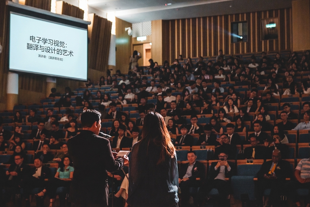 两人在舞台上向座无虚席的讲堂发言