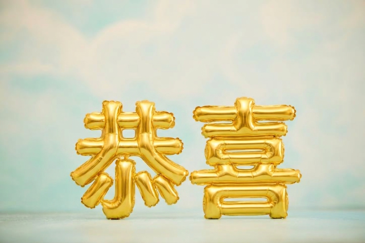 蓝天前写有"congrats"的金色气球