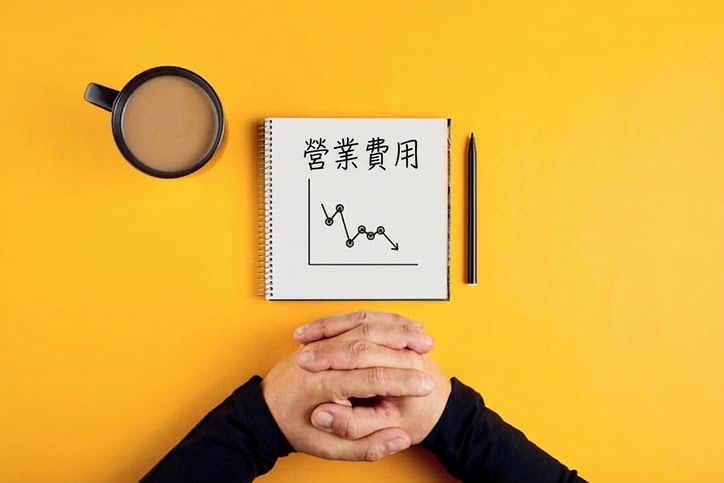 記事本顯示營運費用下降，旁有咖啡杯與男子手臂