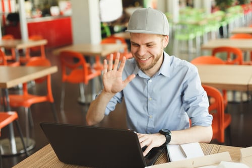 Stock photo of man waving at computer