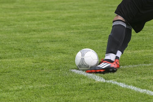 Canva - Soccer Player Kicking White Gray Soccer Ball on Green Grass Field.jpg