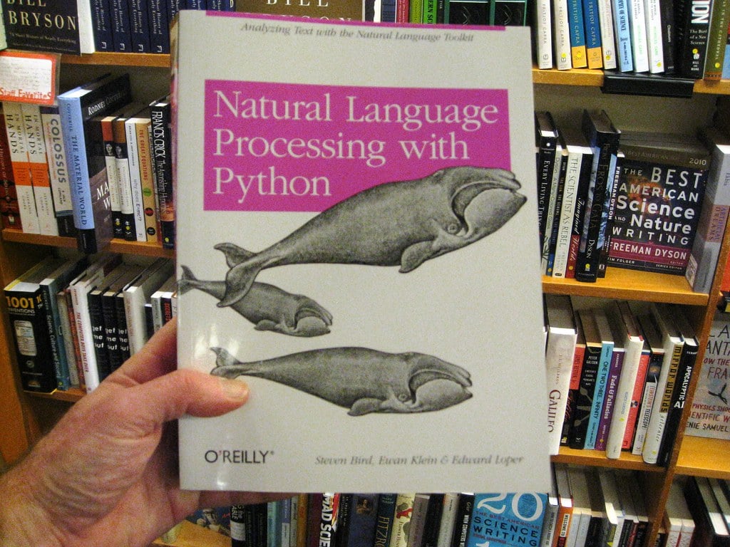 person holding book titled "Natural Language Processing with Python"