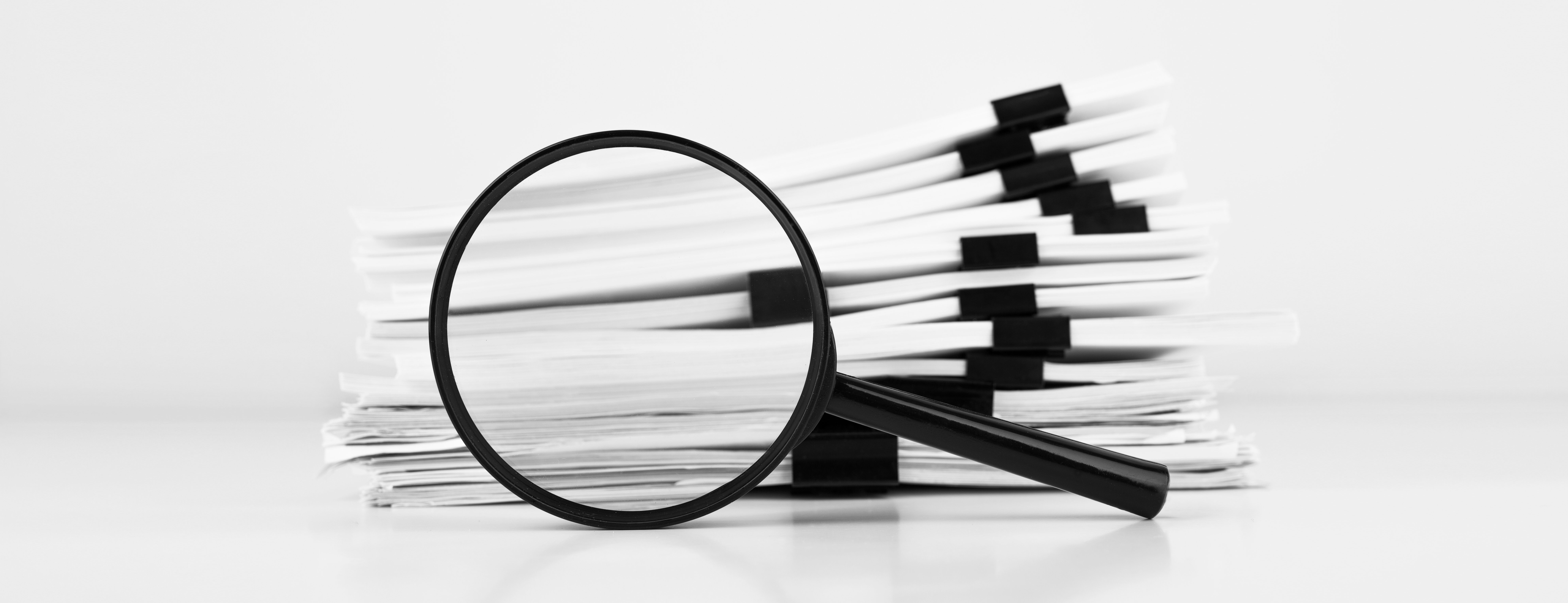 Photograph showing a stack of papers and a magnifying glass