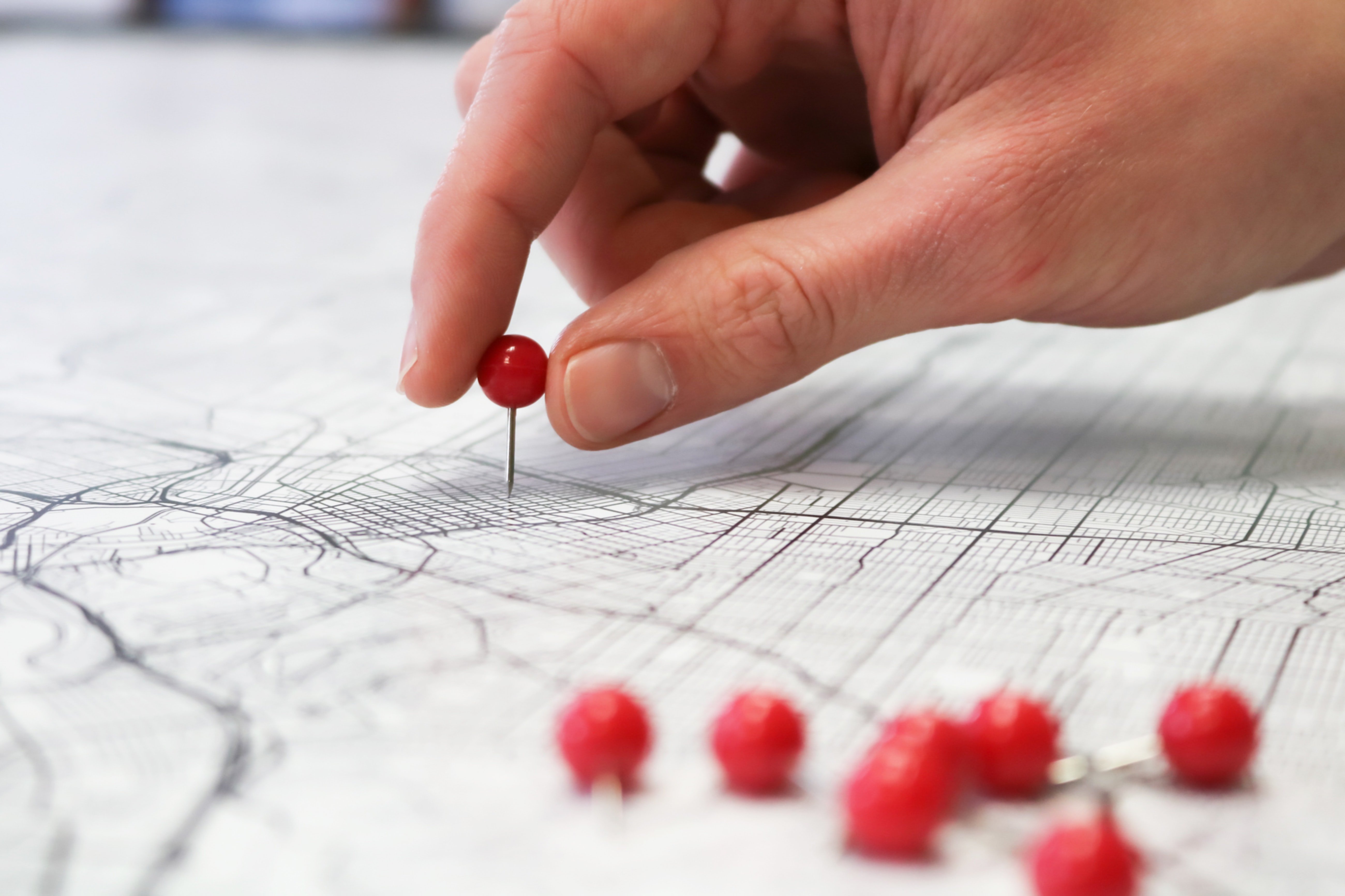 A hand placing a pin on a map