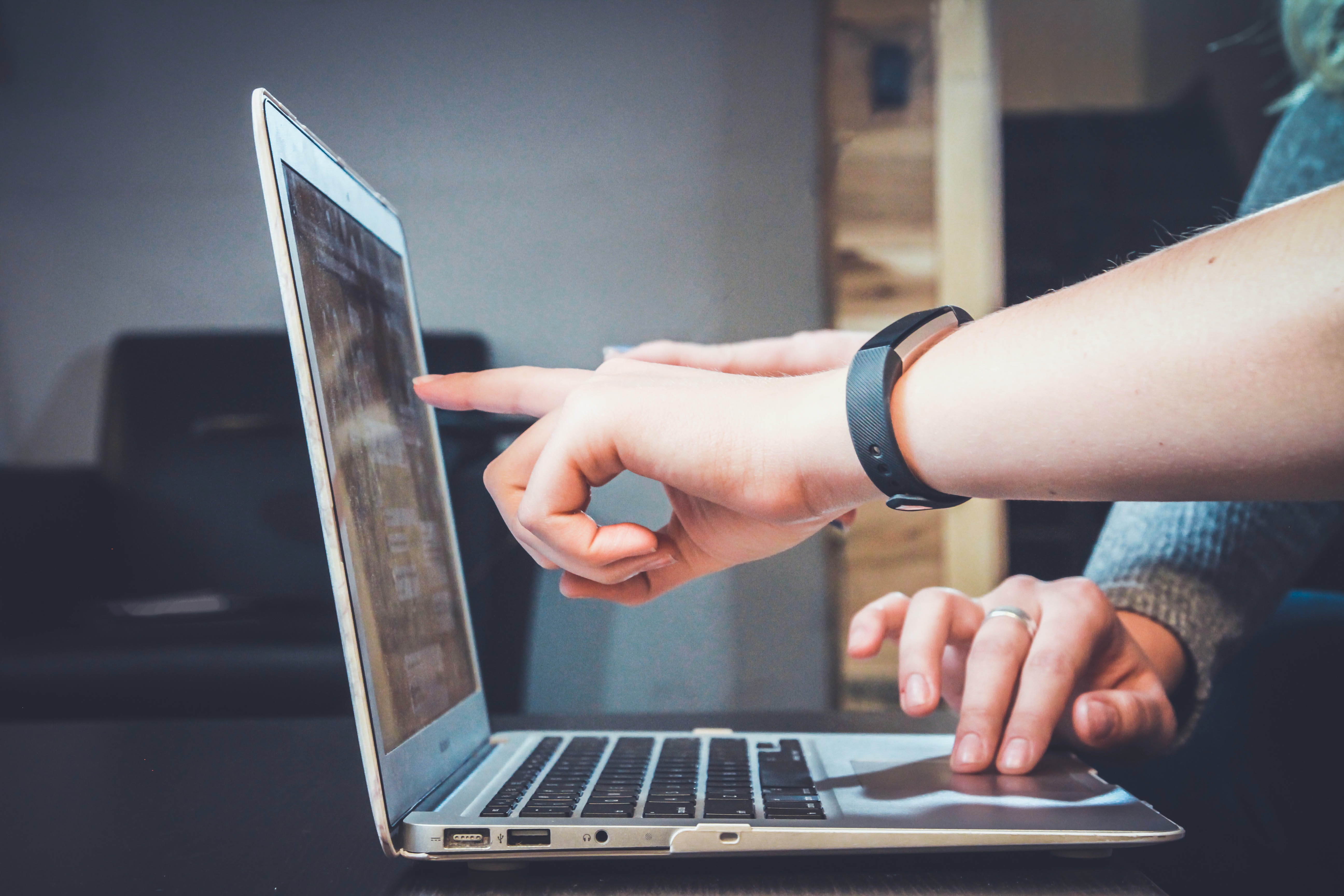 Two persons pointing on the laptop