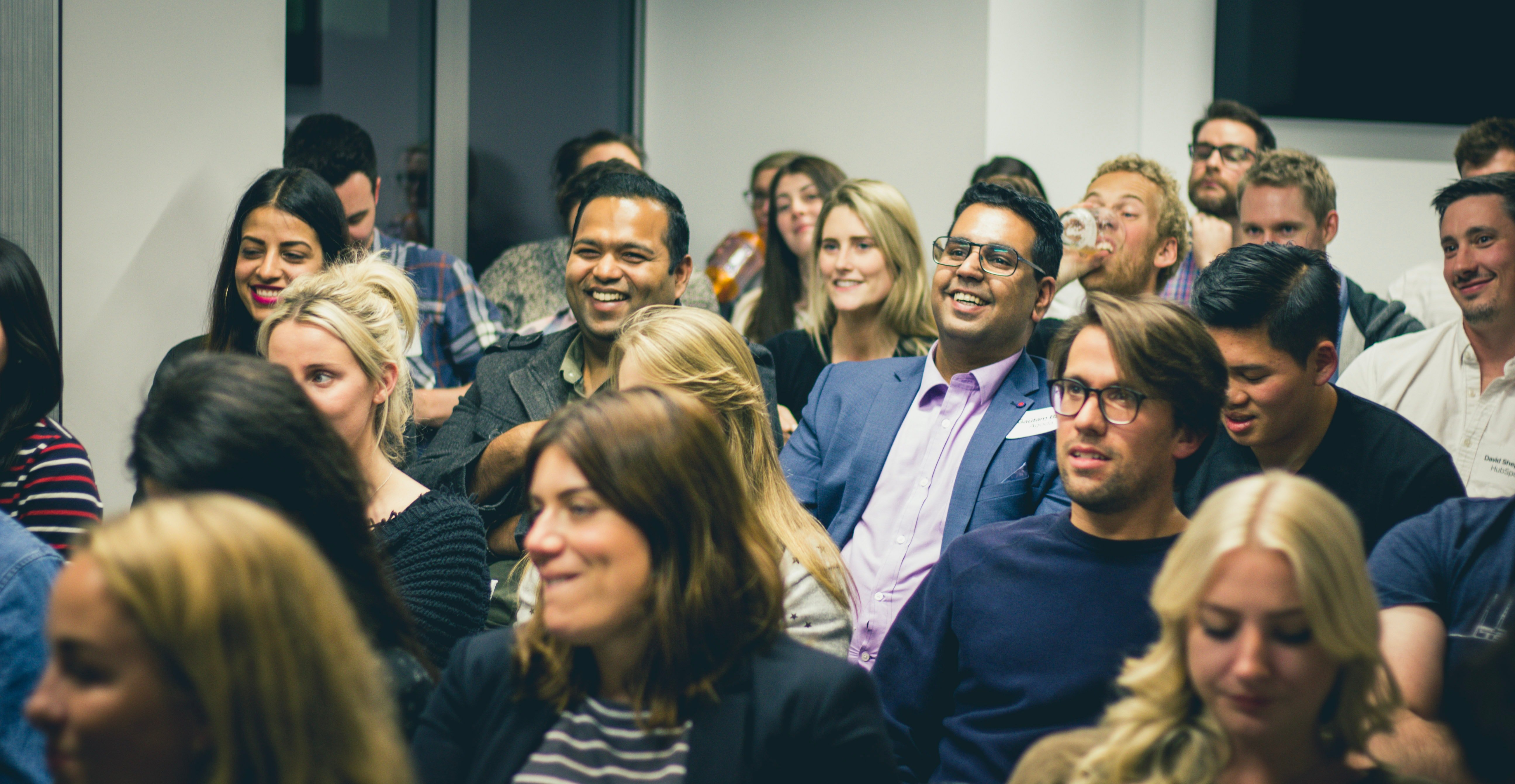 A happy audience of a dozen people in an office are laughing