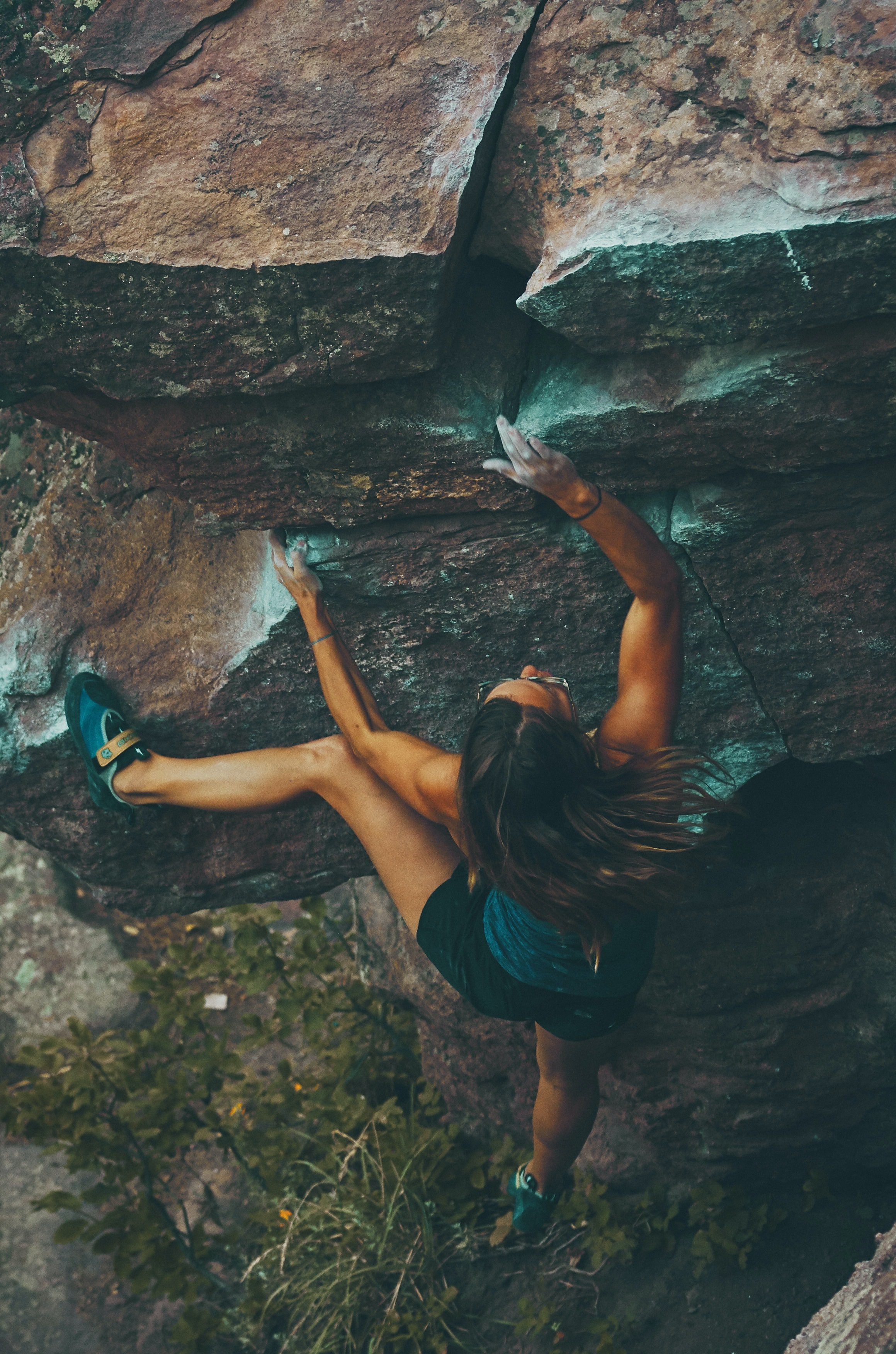 A woman athlete climbs a challenging rock