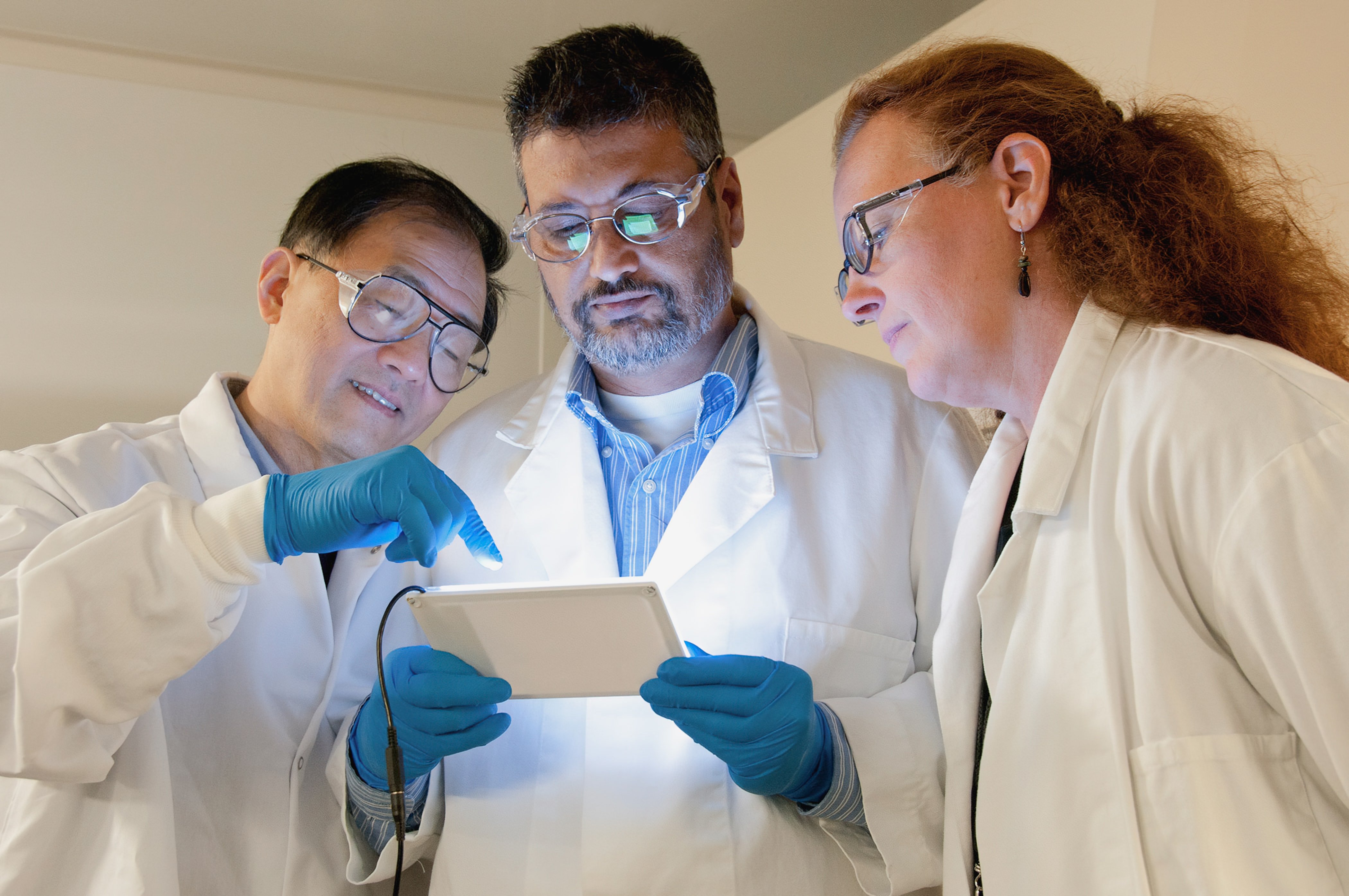 Three researchers standing around a tablet