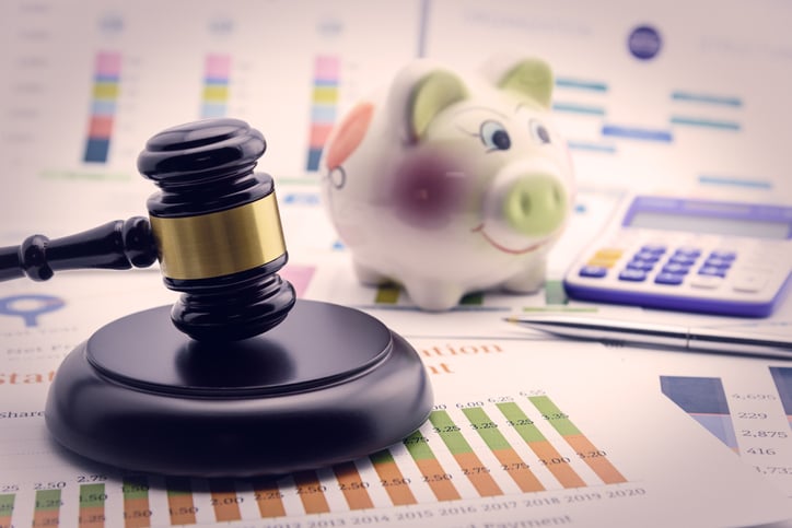 A gavel next to a piggy bank and calculator to represent financial regulations