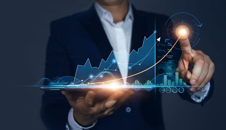 A man's finger pointing to the top of a graph to indicate increased performance