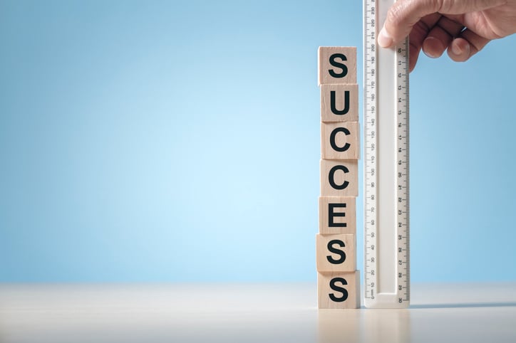 A ruler held up to blocks reading success to demonstrate measuring of progress