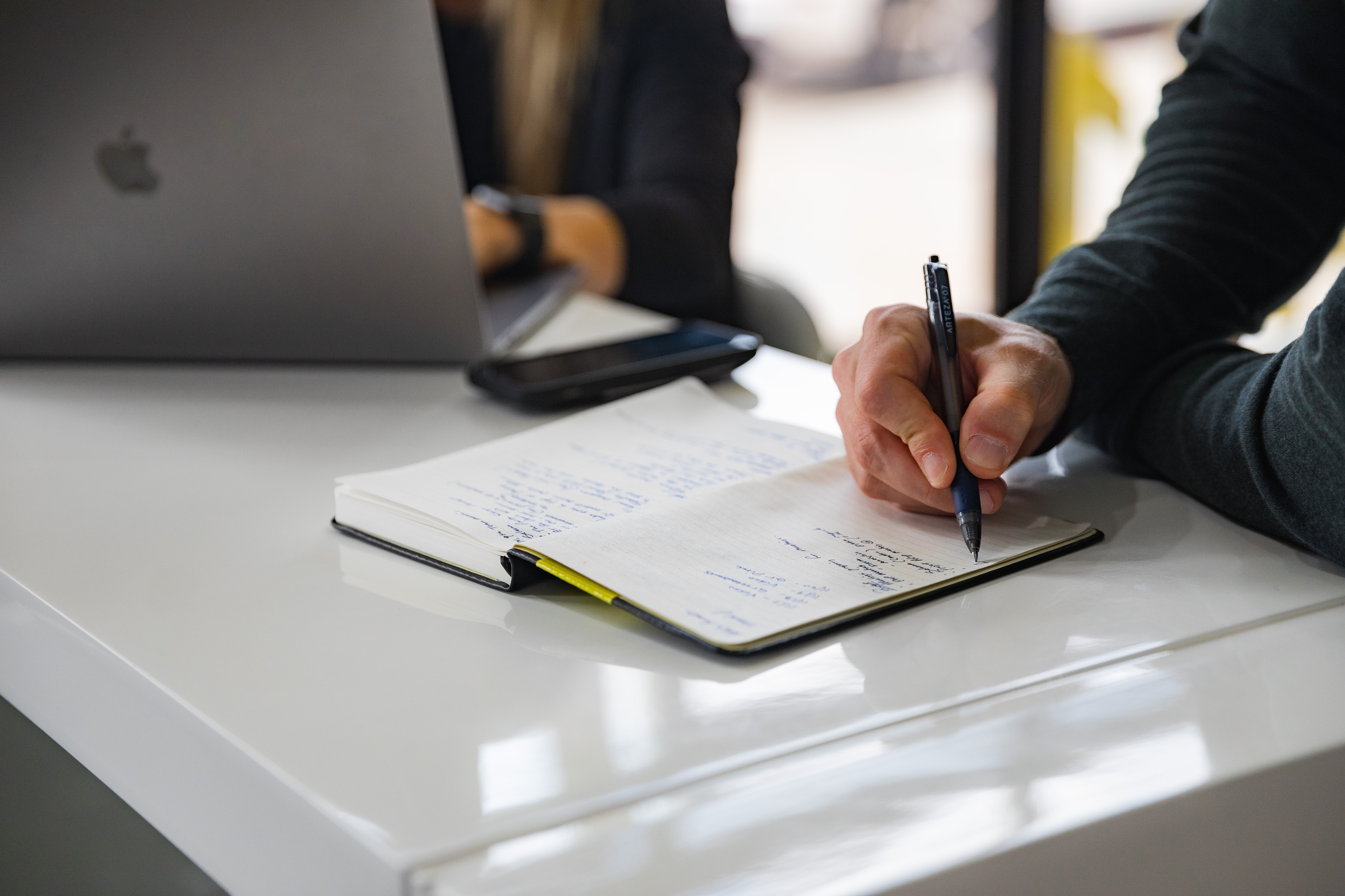 A business professional writes down meeting notes.
