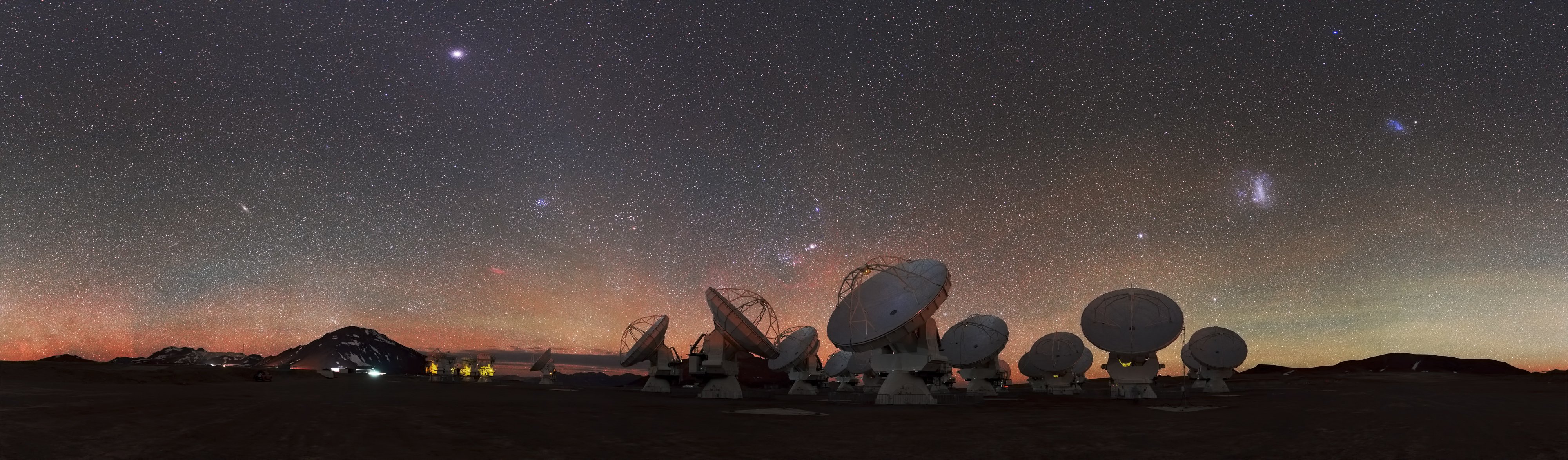 Photo of a several antennas pointing towards a sky full of stars. The image is meant to illustrate a large space, difficult to fully explore.