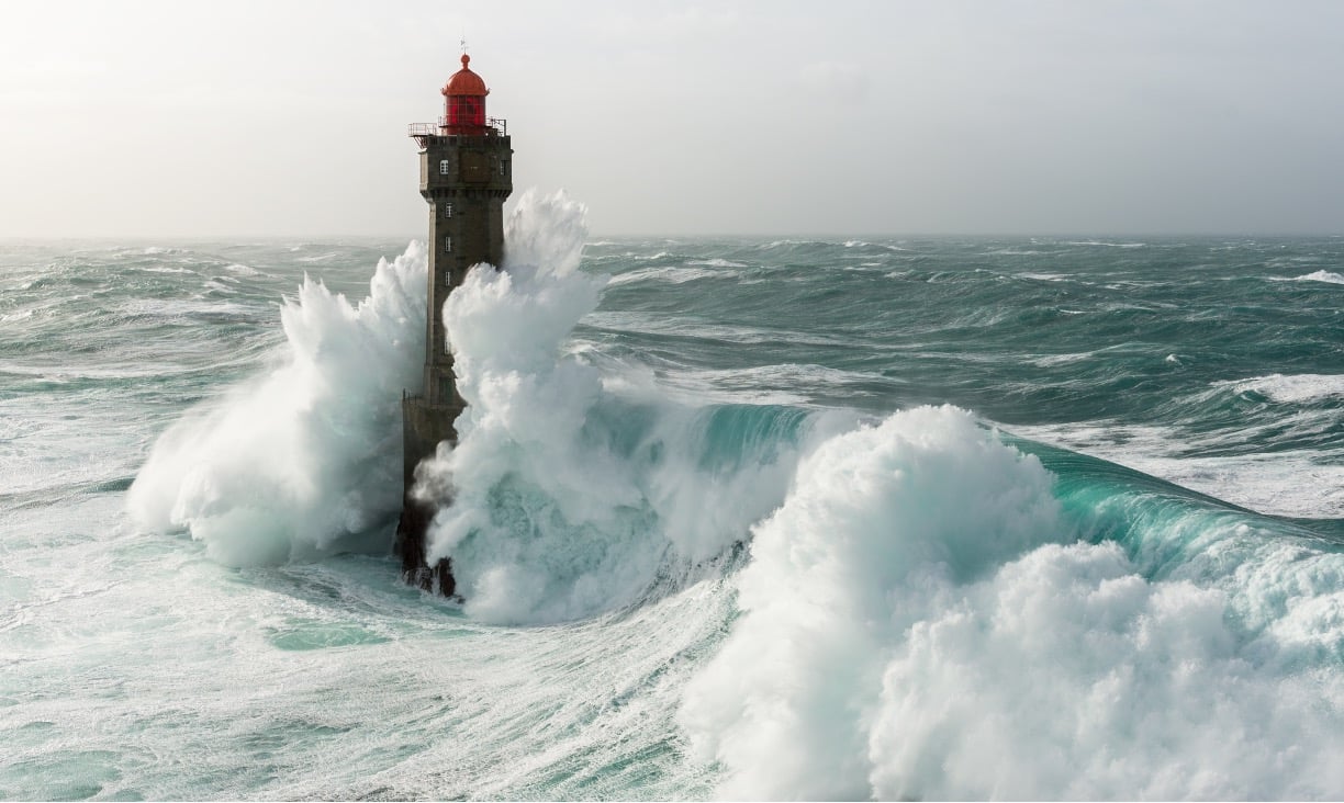 Photo of waves hitting a lighthouse.
