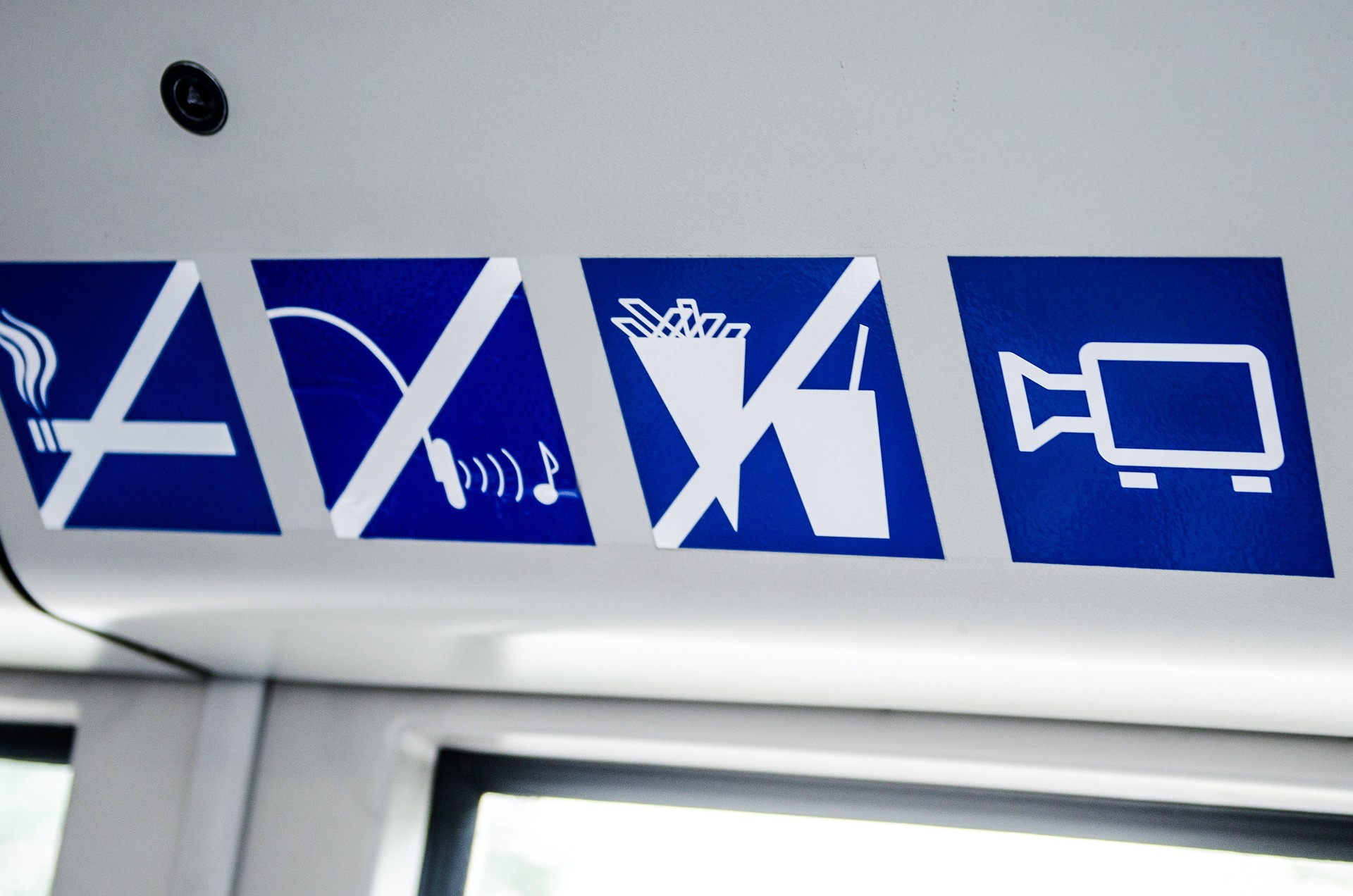 Picture of inside of a train with labels showing that smoking, noises and eating are not allowed and a camera sticker to show that it has video surveillance