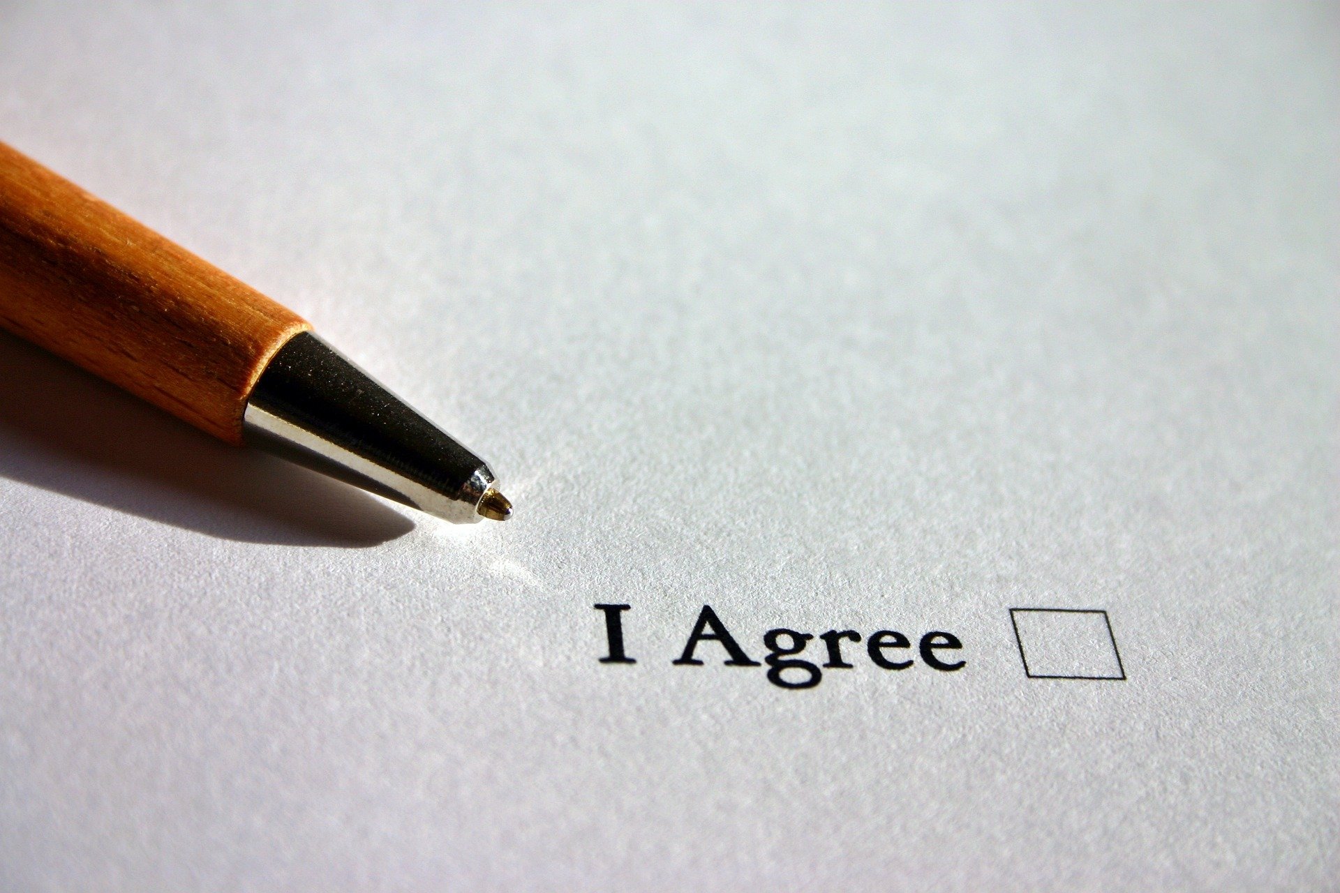 Photo of a pen on top of a paper with an I agree checkbox.