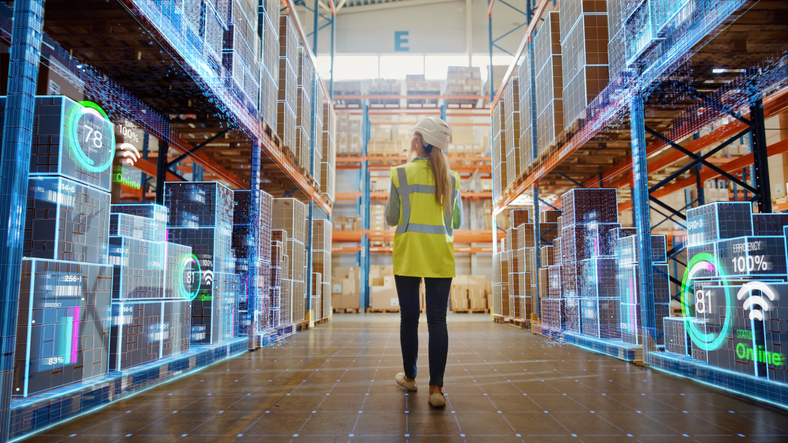 Factory worker inspecting warehouse with inventory analysis showing up along shelves holding products.