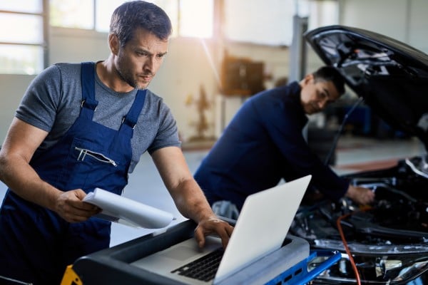 The image shows a worker manually verifying something on a computer.