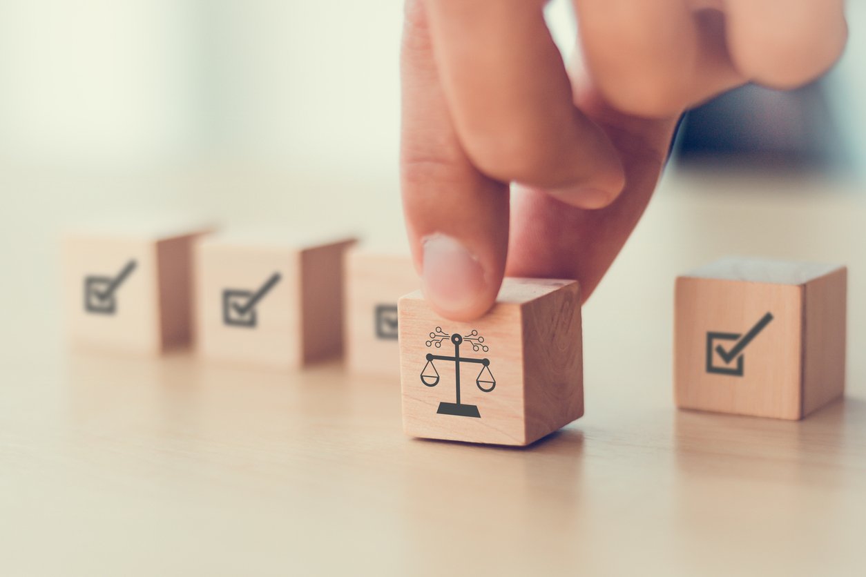 The image shows a wooden block with scale on it, being moved forward that symbolizes greater justice in the system, resulting in reduced bias.