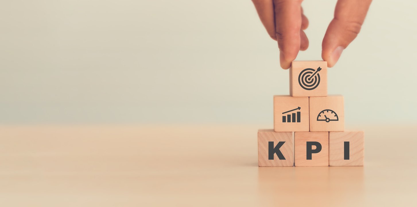 The image displays a pyramid made up of six wooden blocks. The base layer involves creating a KPI from each letter on every block. The remaining layers represent growth, goal achievement, and increased efficiency.