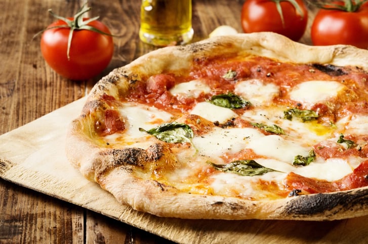 A pizza with mozzarella, red sauce and basil leaves