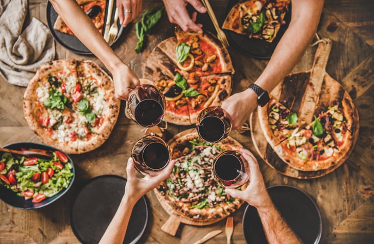Multiple pizzas and wine glasses