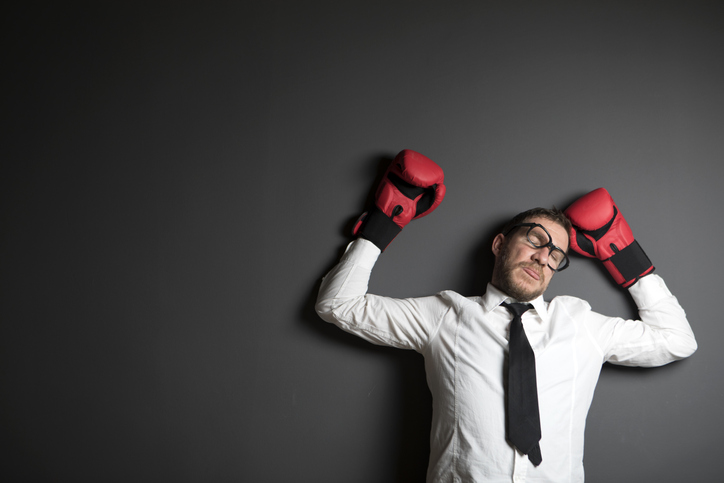 A man wearing boxing gloves after being knocked from a punch