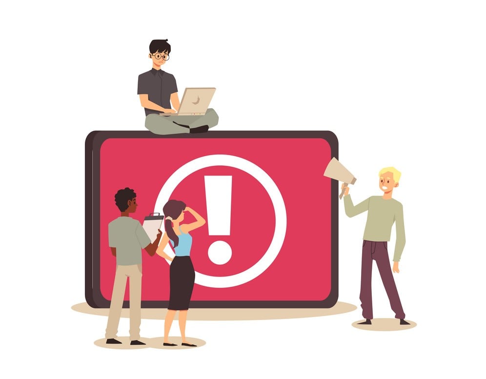 Programmers examine a large exclamation mark in red on the screen.