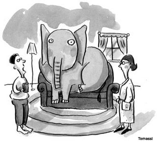 An elephant sits on the couch in a living room and people acknowledge its presence.