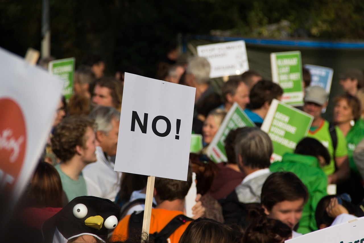 A protest with a protester holding a sign that says “No!”