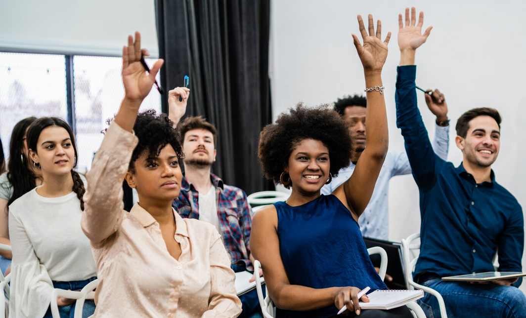 Individuals raising hands in a classroom.
