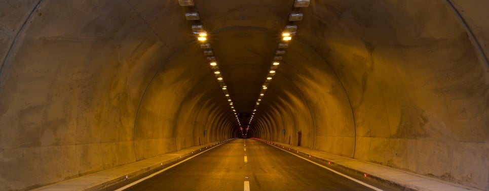 An empty lit road tunnel at night.