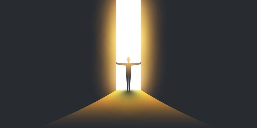 Image of a person open a large dividing door, letting in the lghit from behind