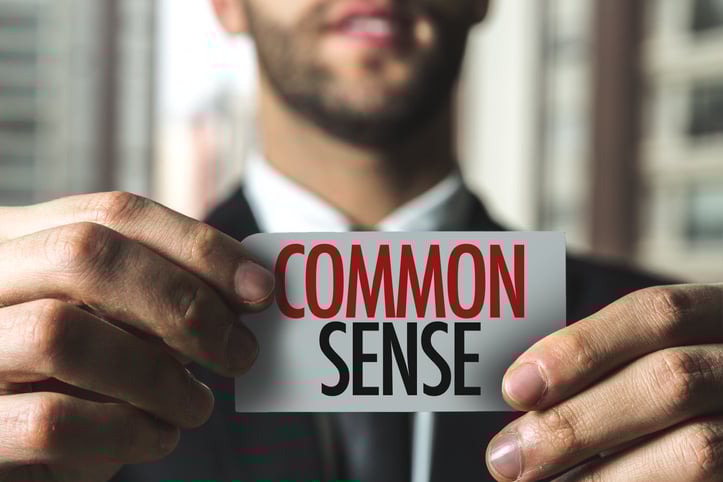 Man holding up a label that has "common sense" written on it