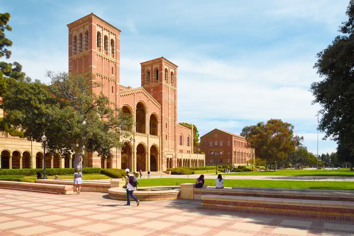 A university building and it's courtyard with a few students walking in and out.
