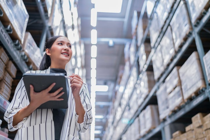 A person uses a tablet device to check items in a warehouse.