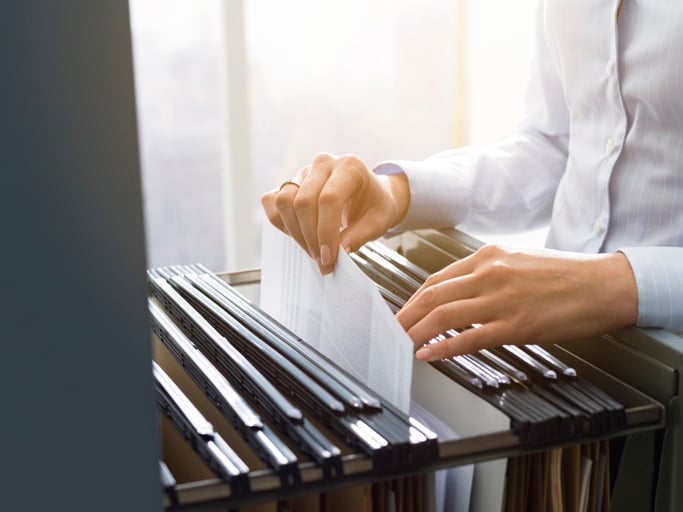 A person files a document in a filing cabinet.